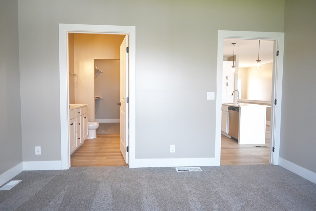 A room with a carpeted floor and two open doors leading to other rooms.