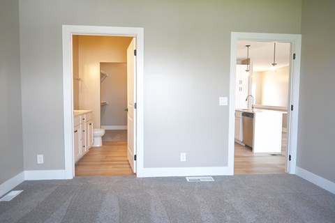 A room with a carpeted floor and two open doors leading to other rooms.