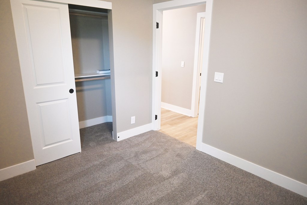 A room with a white door and a carpeted floor.