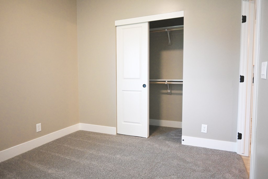 A room with a white door and a grey carpet.