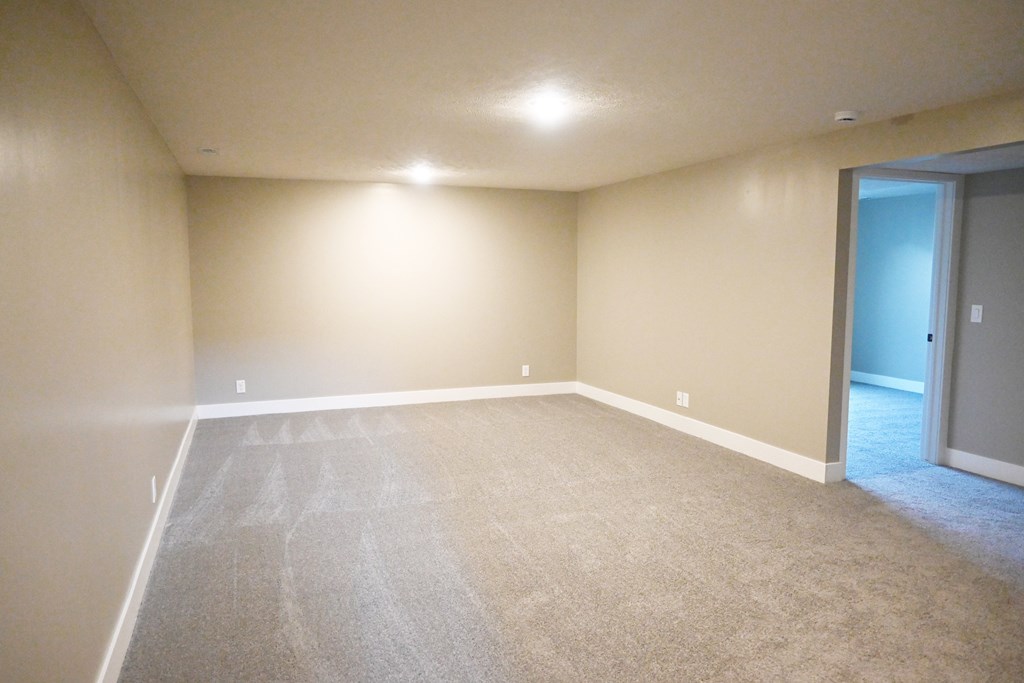 A room with a carpeted floor and a door on the right side.