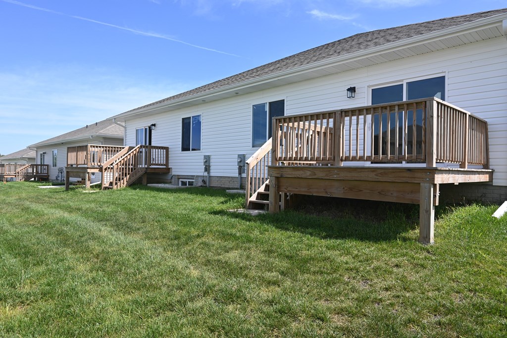 A white house with a wooden deck in front.