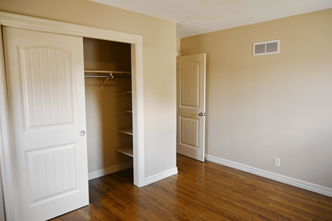 A room with a white door and a white closet with a shelf.