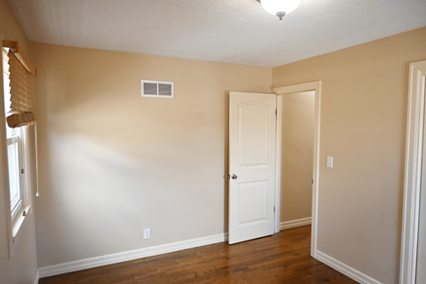 A room with a white door and a window with blinds.