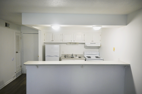 A white kitchen with a refrigerator, oven, and cabinets.