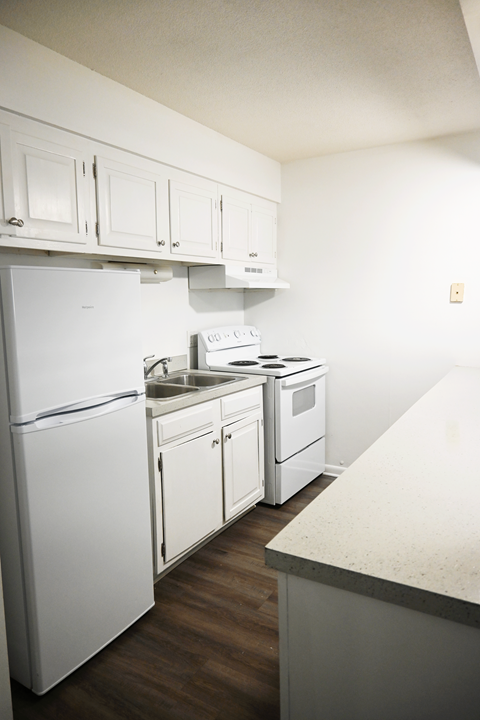 A white fridge and oven in a kitchen with wooden floors.