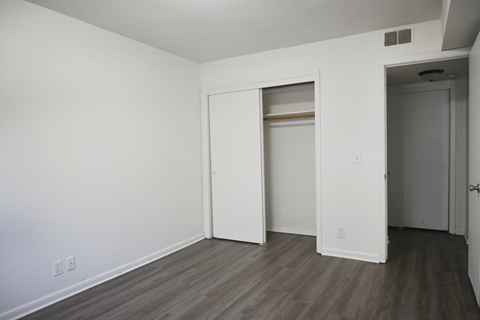A room with a white door and a brown floor.