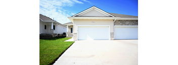 Exterior view of a townhome with attached garage, concrete driveway, siding, and lawn at 8212 & 8208 Townhomes.