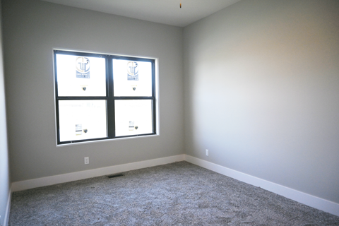 A room with a carpeted floor and a window with blinds.