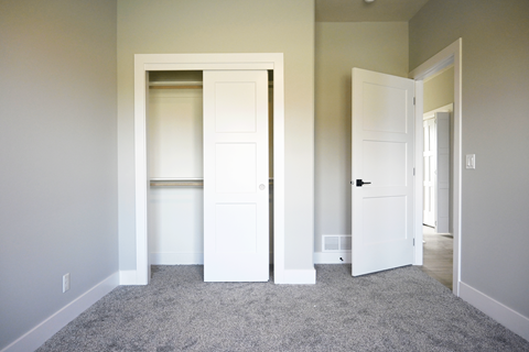 A room with a carpeted floor and two white doors.