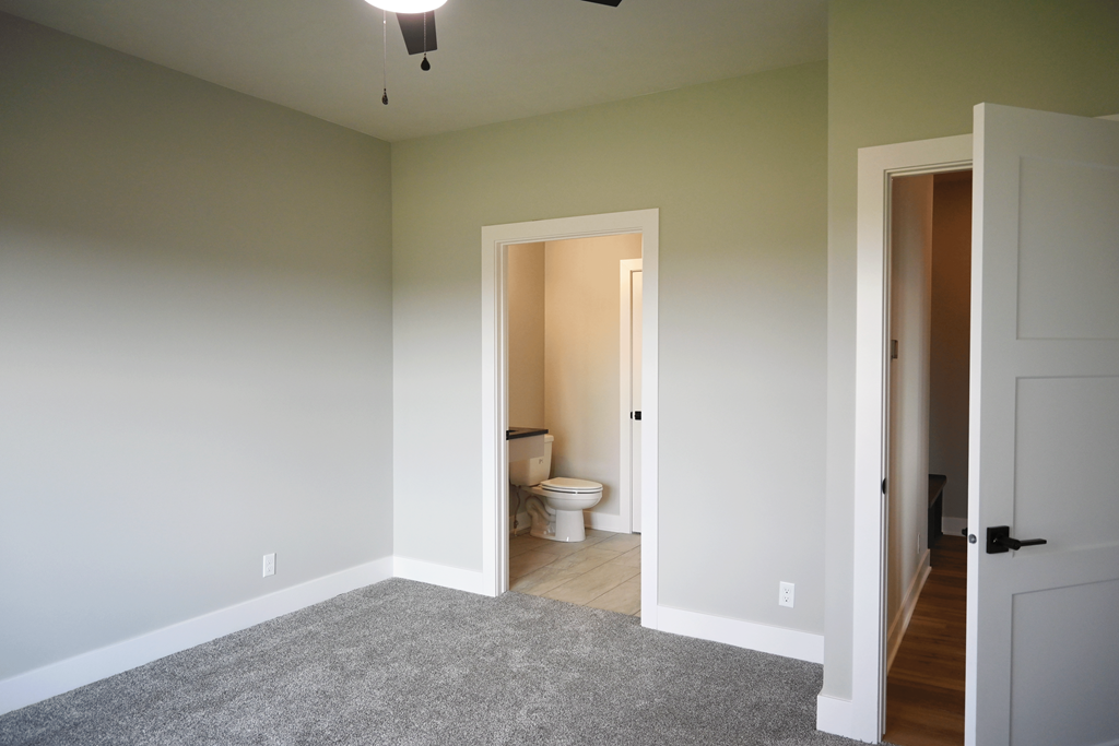 A room with a toilet in the middle and a doorway leading to another room.