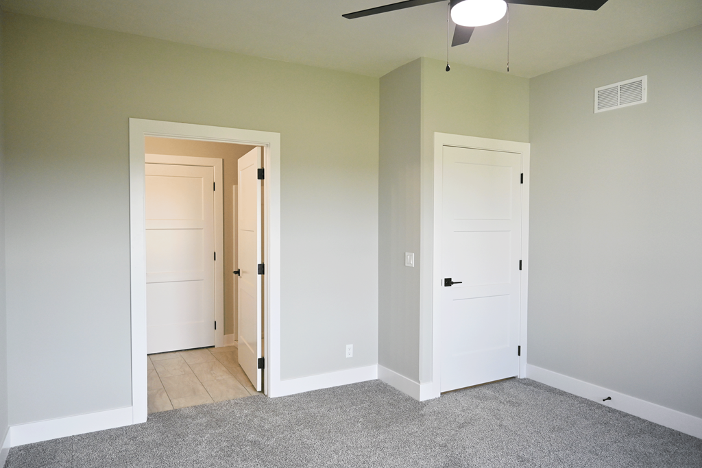 A room with a ceiling fan and two doors.