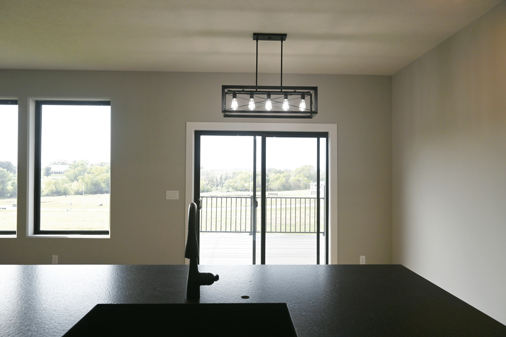 A room with a black table and a view of a parking lot through a glass door.