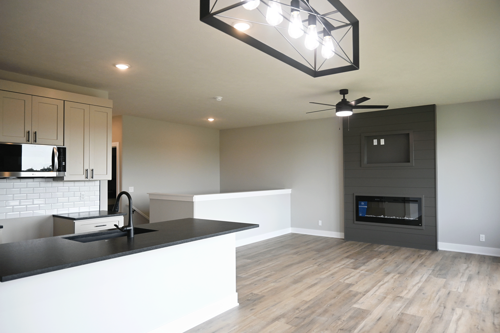 A modern kitchen with a black countertop and a fireplace in the living room.