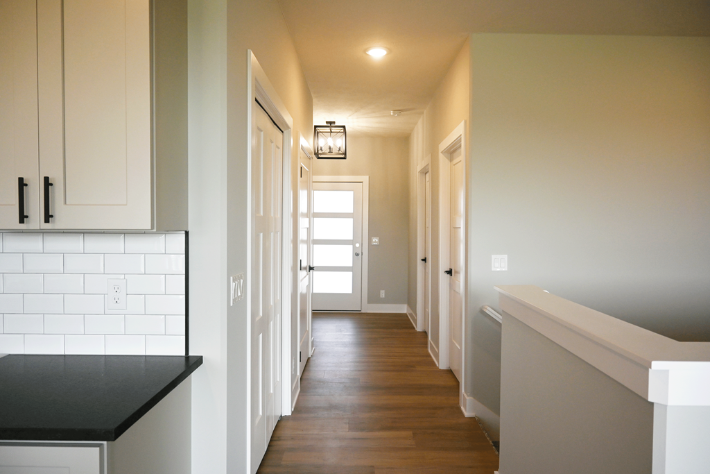 A long hallway with white walls and wood floors.