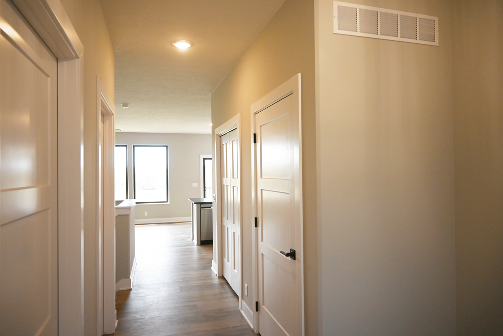 A long hallway with white doors and a window.