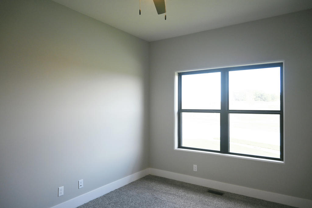 A room with a window and a carpeted floor.