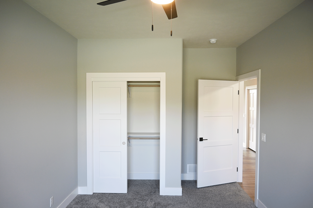 A room with a ceiling fan and two doors.