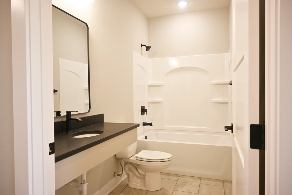 A white toilet is in a bathroom with a black counter top.