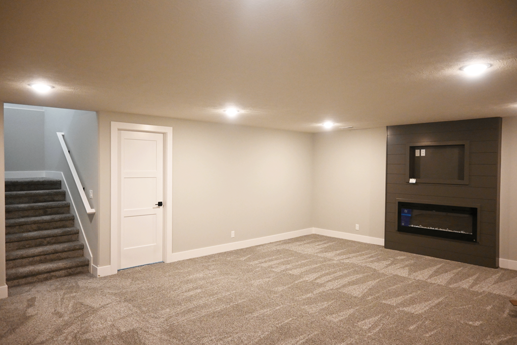 A spacious living room with a fireplace and a staircase.
