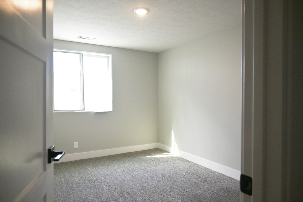 A room with a carpeted floor and a window.