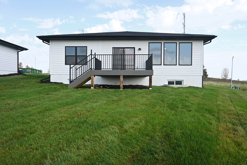 A white house with a black roof and a balcony.