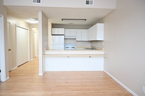 A kitchen with white cabinets and a wooden floor.