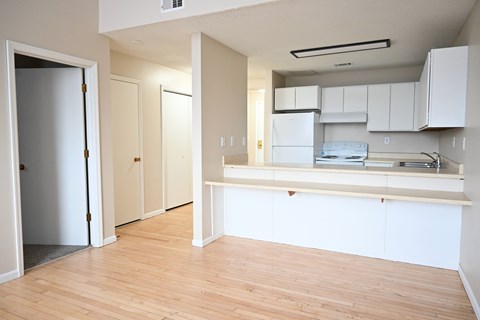 A kitchen with white cabinets and a wooden floor.