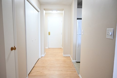 A hallway with a wooden floor and white walls.