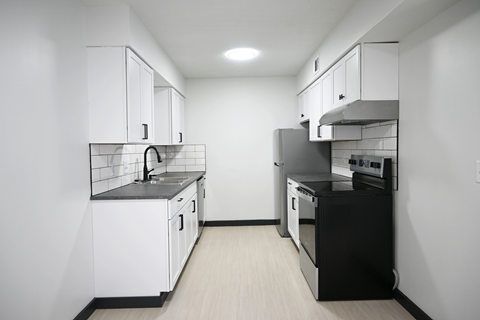 A kitchen with white cabinets and black appliances.