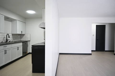 A kitchen with white cabinets and black appliances.