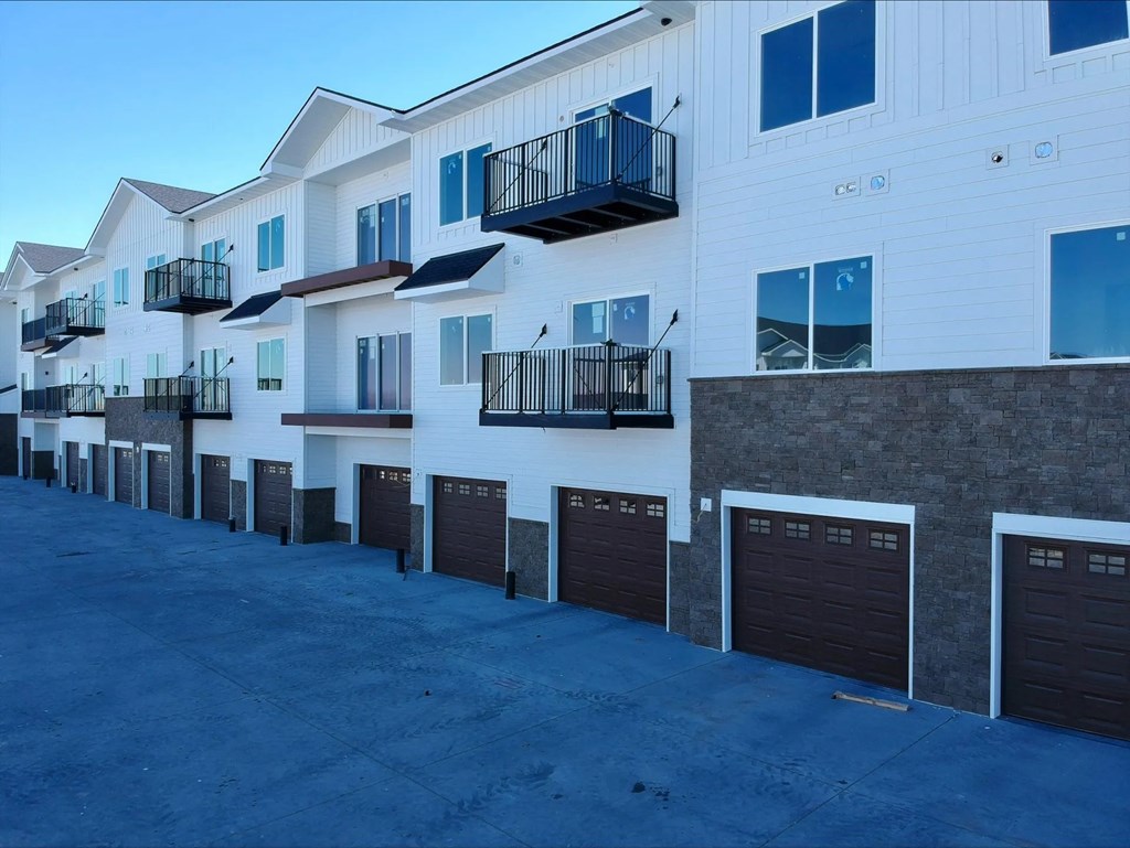 Apartment building with balconies and garage doors.