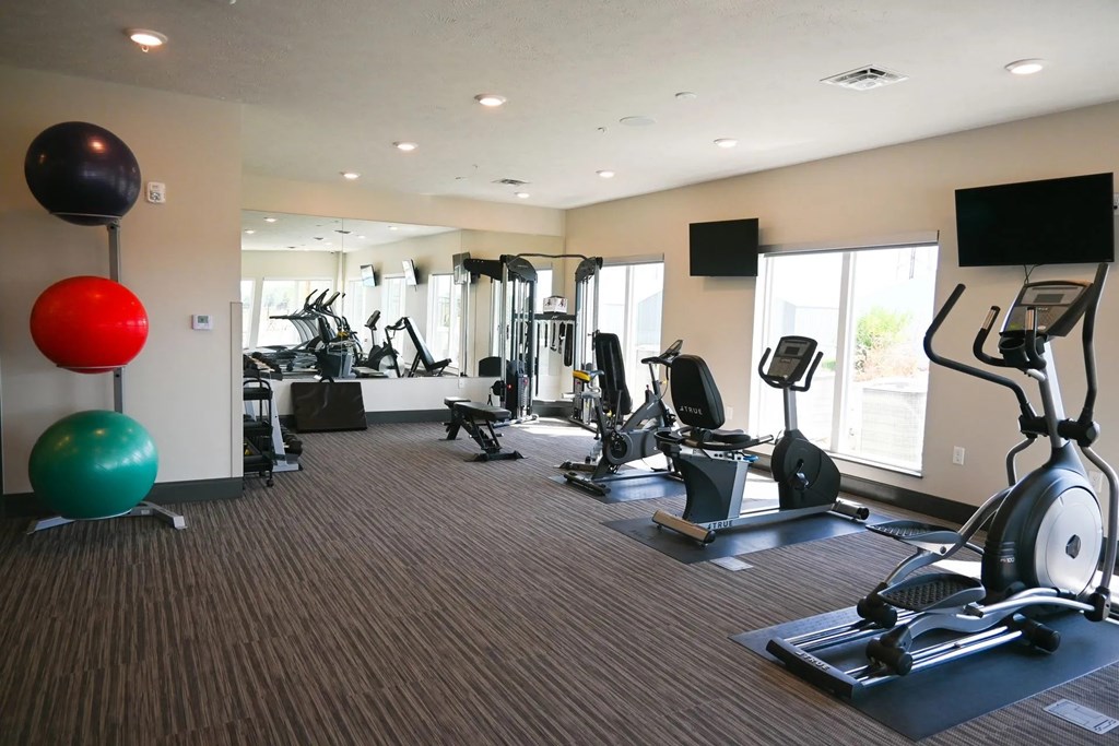A gym with a variety of exercise equipment including treadmills, stationary bikes, and weight machines.
