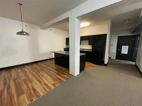 A room with a wooden floor and a grey carpet.