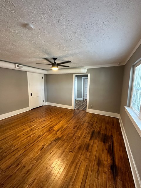 A room with a ceiling fan and wooden flooring.