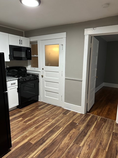 A kitchen with a black fridge and stove top oven.