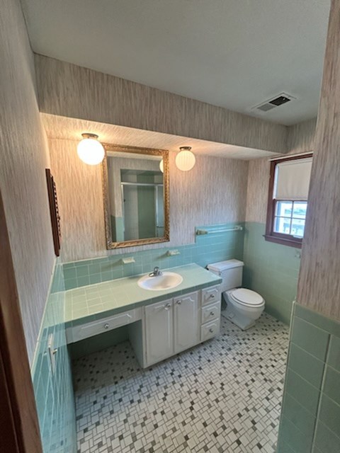 A bathroom with a sink, toilet, and mirror.