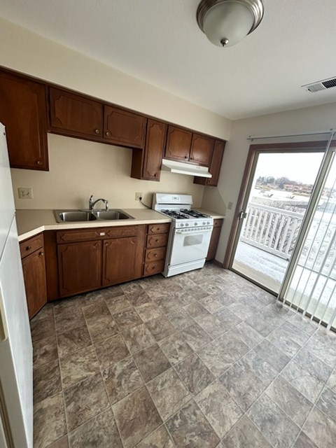 A kitchen with brown cabinets and a white fridge.