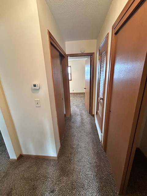 A hallway with a carpeted floor and white walls.