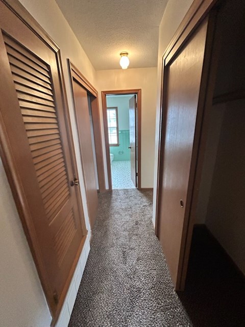 A hallway with a light on and a door at the end.