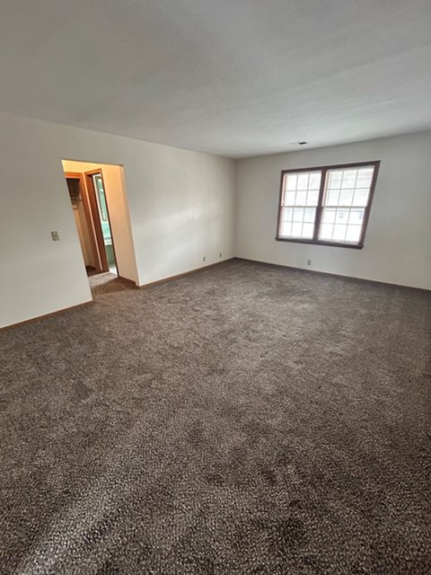 A room with a carpeted floor and a window.
