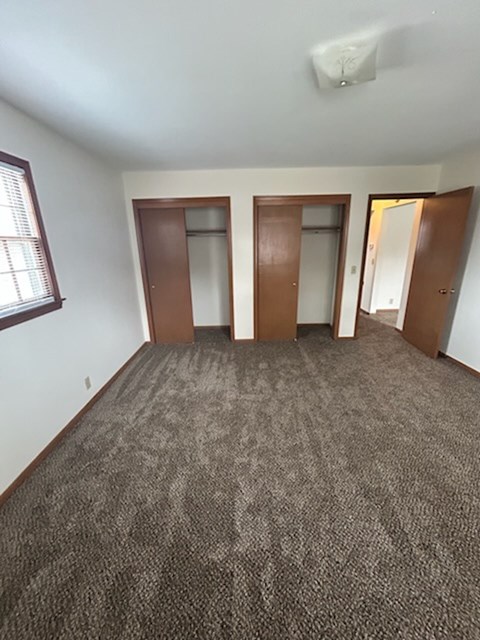 A room with carpeted floor and three doors.