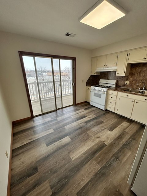 A kitchen with wooden floors and white cabinets.