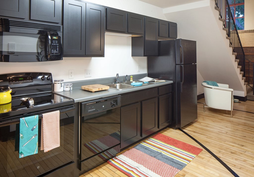 A kitchen with black cabinets and a wooden floor.