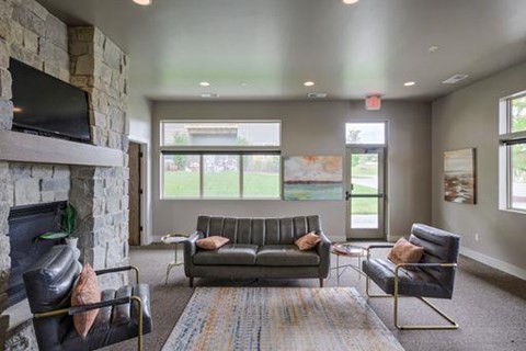 A living room with a grey couch and a stone fireplace.