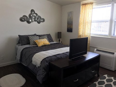 A bedroom with a bed, a television, and a painting on the wall.