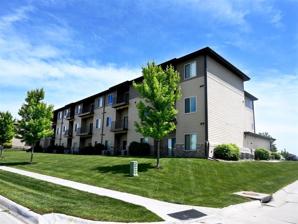 A large apartment building with a green lawn in front.