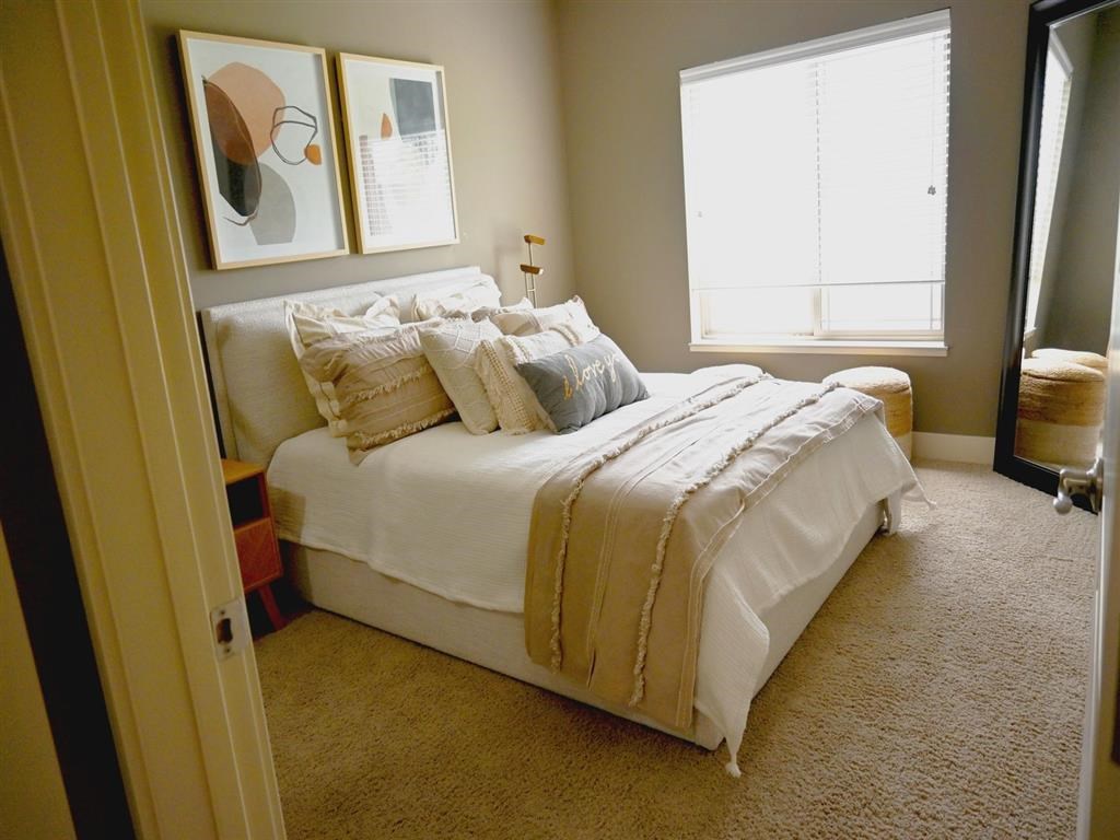 A bedroom with a large bed and two framed pictures on the wall.