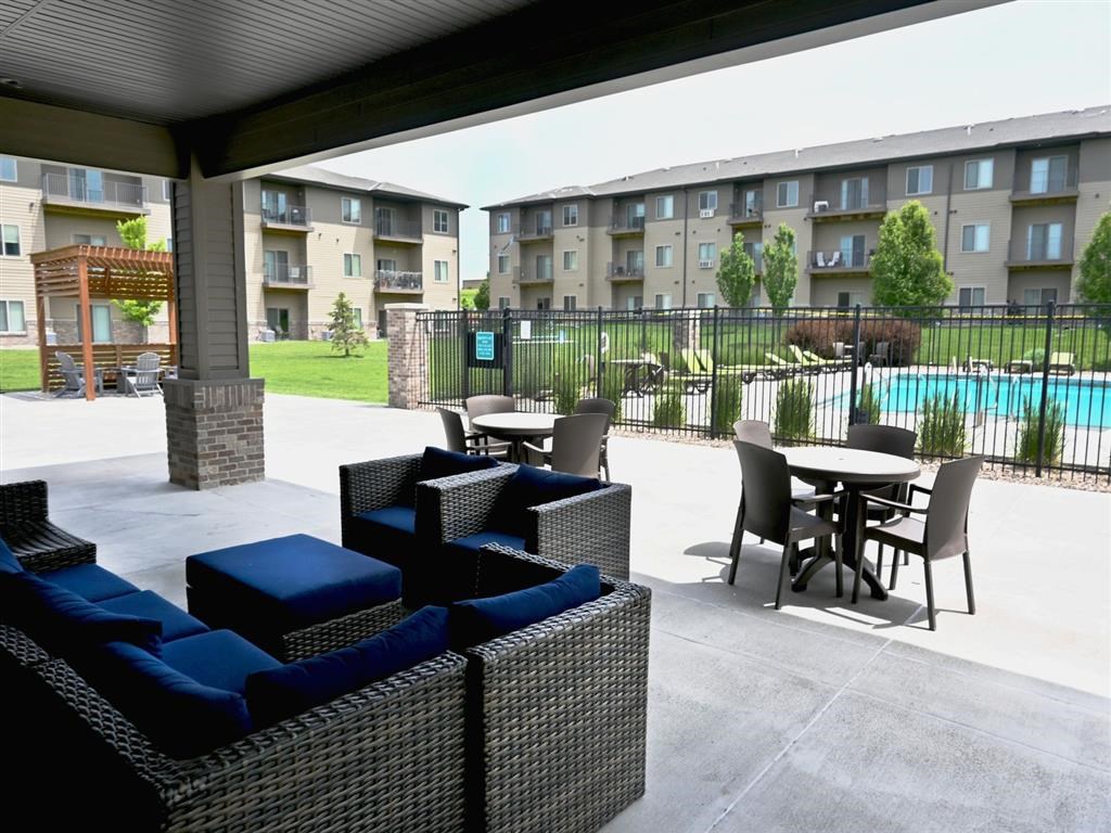 A patio with a table and chairs and a pool in the background.