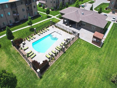 A swimming pool surrounded by a concrete border and lounge chairs.